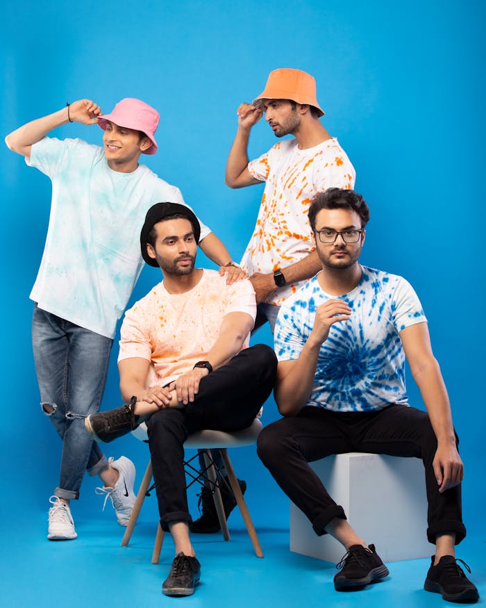 A stylish group of men posing in colorful tie-dye T-shirts in a studio setting.